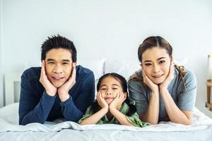 familia joven feliz divirtiéndose en la mañana en la cama juntos y mirando a la cámara foto