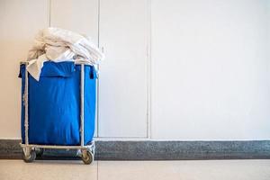 Trolley full of dirty white sheets of guests in a hotel, Copy space for text, Concept of room service tool and equipment. photo