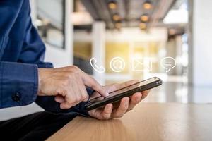 Hotline service, Customer support hotline Contact us people connection. Businessman using Smart Phone with the email, call phone, address, Chat message icons photo