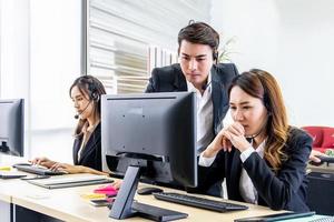 grupo de jóvenes con computadora de escritorio en fila y capacitación en auriculares con instructor en el centro de negocios de la línea de ayuda de atención al cliente foto