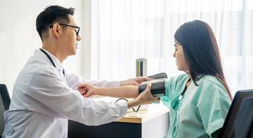 concepto de salud, hospital y medicina - médico que mide la presión sanguínea de su paciente en el hospital foto