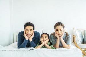Happy young family having fun in the morning in bed together and looking at camera photo