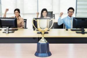 Close up of a trophy in front of a working business people, achieve business concept. photo