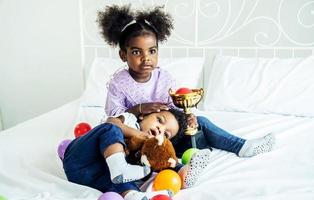 Happy cute active little african american kids boy and girl relaxing on bed at home photo