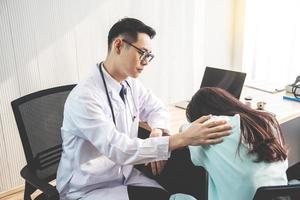 un médico amable que consuela a una paciente y usa su mano a hombro para ayudarla a relajarse en el consultorio durante la recepción, el concepto de asesoramiento y atención médica. foto