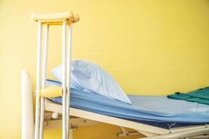 Empty bed with pillow and blanket and intravenous stand and walking stick, Walking stick cane used by disable patient for balancing, Healthcare,medical insurance and Physical therapy concept. photo