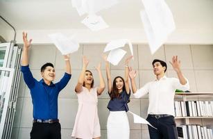 grupo de jóvenes empresarios confiados feliz sonrisa celebrando lanzando sus documentos comerciales al aire, concepto de equipo de éxito después de firmar contrato foto