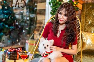 hermosa joven asiática sonriente sentada en un café restaurante sosteniendo un encantador perro pomeraniano, gente con tema de perros. foto