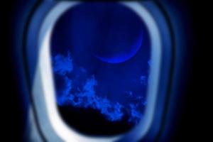 cielo nocturno con nubes y luna visto desde el interior de las ventanas de un avión, concepto de viaje y transporte aéreo foto