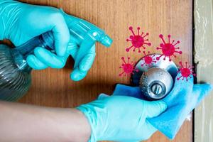 Hand in gloves cleaning door knob with alcohol spray. Corona virus or bacteria infected protection. photo