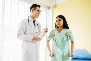 Front view of Asian male doctor helping female patient to walk out the hospital bed, Medicine and health care concept, selective focus point photo