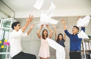 Group of young confident business people  happy smile celebrating  by throwing their business papers in the air, success team concept after sign contract photo