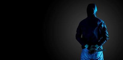 concepto de asesinato, muerte y personas - criminal o bandido sosteniendo un cuchillo detrás de su espalda, aislado en fondo negro foto