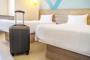 maleta de viaje negra o bolsa de equipaje en una habitación de hotel moderna: tiempo de relajación, vacaciones, fin de semana y concepto de viaje.