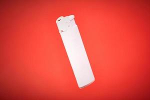 Plastic cigarette lighter on red background, white disposable gas igniter photo