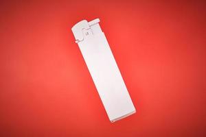 Plastic cigarette lighter on red background, white disposable gas igniter photo
