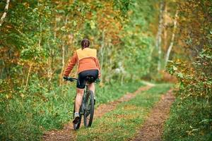 Female mountain biker riding on bike in nature, off-road trail, sports, fitness, health photo