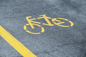 Yellow bicycle sign on sidewalk, road yellow marking for traffic safety near highway photo