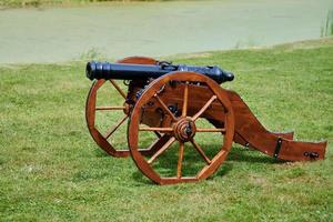 Artillery cannon model for castle defense, green lawn background, protect against attack of enemy photo