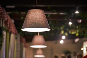 Pendant lamps over tables in restaurant. Modern pendant low dimmed warm light with lampshades photo