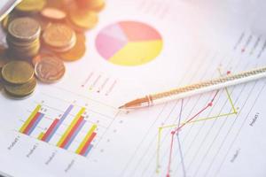 Business report graph chart with coin and pen on report paper document present financial on table office background photo