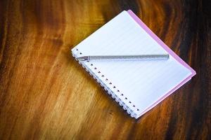 cuaderno de bocetos con páginas en blanco de bolígrafo o cuaderno sobre fondo de madera - suministros de oficina de papel de cuaderno o concepto de educación foto