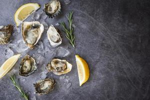 Fresh oysters seafood on black plate background Open oyster shell with herb spices lemon rosemary served table and ice healthy sea food raw oyster dinner in the restaurant gourmet food photo