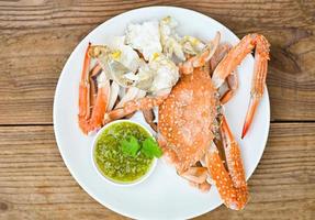 seafood plate fresh crab cooking on white plate background , blue swimming crab meat claw served on a food table - cooking steamed crab with seafood sauce top view photo