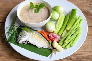 Thai food mackerel cooking, mackerel fish for cooked with chili shallot garlic green brinjal cucumber fresh vegetables on white plate fish meal photo
