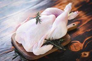 Rosemary chicken meat - fresh raw chicken whole on wooden board on white wood background photo