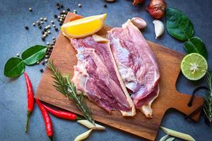 Raw duck breast with herb spices ready to cook on wooden cutting board, Fresh duck meat for food photo