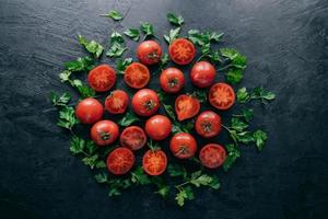 Shot of red ripe tomatoes and green fresh parsley on dark background. Vegetable composition. Healthy nutrition concept. Organic food
