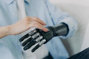 Hands of handicapped girl setting up her bionic arm and pressing buttons. Robotic bionic prosthesis. photo