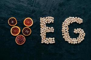 Food letters. Garbanzo and slice of citrus fruit in form of veg letters on dark background. Organic ingredients for vegetarians. Healthy products photo