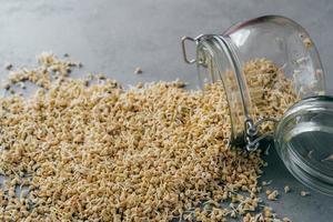 Horizontal shot of buckwheat sprouts in glass jar on grey background. Eco nutrition. Fitness and dieting concept. Germinated buckwheat seeds photo