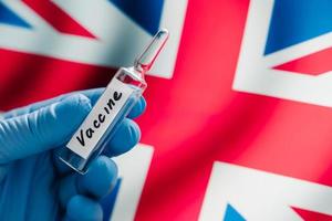 New coronavirus vaccine against UK flag as background. Fight against Covid-19. British medical research and vaccination. Medicine concept photo