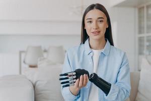 feliz mujer joven discapacitada está ensamblando prótesis de extremidades biónicas. chica atractiva tiene mano cibernética. foto