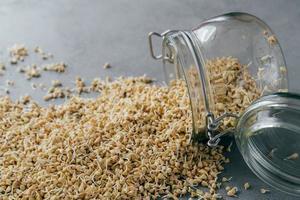 Healthy nutrition and dieting concept. Fresh buckwheat sprouts spilled on grey background from glass jar. Vegetarian dish full of vitamins photo