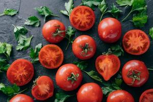 Fresh vegtables on dark background. Ripe red tomatoes and green parsley harvested from garden. Water drops on organic products. Tasty vegan products photo