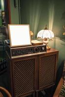 Antique audio player with blank frame and lamp shining on wood closet photo