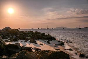 Tropical sea with rocks on coastline at sunset photo