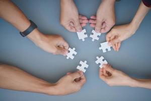 The hands of a variety of people including the Asian jigsaw puzzle And gather parts to find suitable partners to support teamwork to find common problem solving concepts, close-up perspectives photo