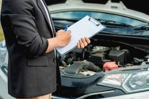 el mecánico está revisando el motor y las notas en un libro blanco. foto