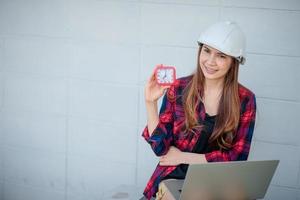 A female construction engineer looking at a watch and a laptop photo