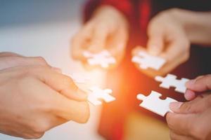 The hands of a variety of people including the Asian jigsaw puzzle And gather parts to find suitable partners to support teamwork to find common problem solving concepts, close-up perspectives photo