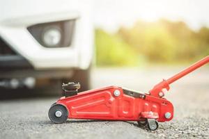 Car Lifted With Red Hydraulic Floor Jack For Repairing photo