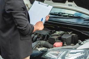 el mecánico está revisando el motor y las notas en un libro blanco. foto