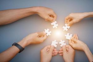 The hand of a businessman holding a paper jigsaw And solve the puzzle together. The business team assembled a jigsaw puzzle. A business group wishing to bring together the puzzle pieces photo