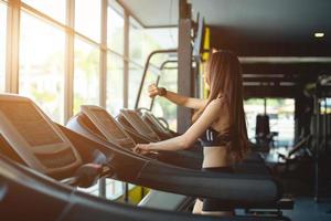 Side view of two attractive sports women on running track. Girls on treadmill photo