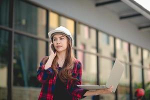 Female construction engineers use laptops and phones photo